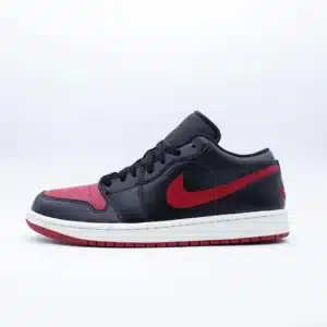Tenis Air Jordan 1 Low Black Red piel negra con punta y logo de Nike en rojo, agujetas negras, mediasuela color hueso y suela roja de hule.
