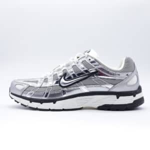 Tenis unisex Nike P-6000 en color plata metálico. Diseño de estilo running retro con capas superpuestas brillantes.