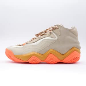 Tenis Adidas x Ivy Park Top Ten 2000 para mujer. Silueta de corte medio en gamuza beige y piel color crema con suela segmentada en tono naranja vibrante.