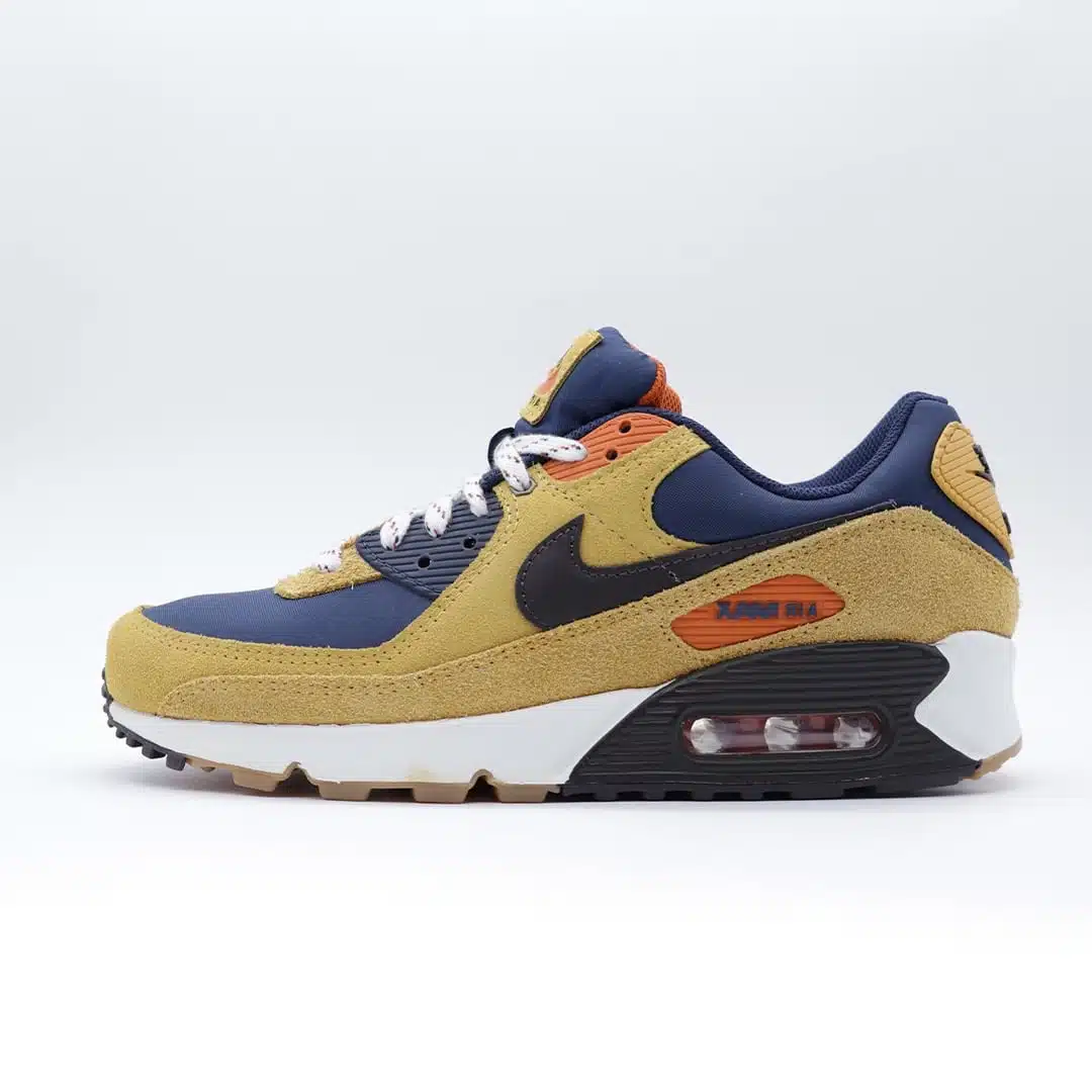 Tenis Nike Air Max 90 en combinación de cuero color tostado y azul marino. Diseño clásico con unidad Air visible.