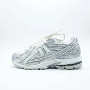 New Balance 1906R Silver Metallic malla gris oscuro con paneles plateados de brillo metálico y silueta curva estilo runner.