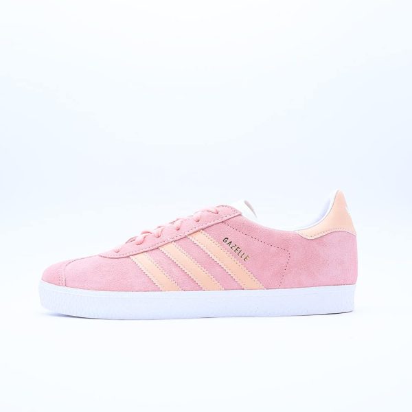 Tenis Adidas Gazelle para mujer. Silueta clásica de perfil bajo en gamuza rosa con las tres franjas en tono naranja claro y suela blanca texturizada.