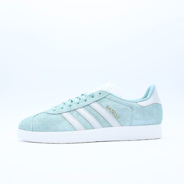 Tenis Adidas Gazelle para mujer. Silueta clásica de perfil bajo en gamuza verde menta con las tres franjas blancas y el icónico grabado dorado.