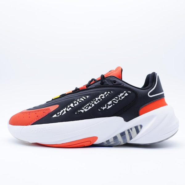 Tenis Adidas Ozelia J infantiles unisex. Silueta audaz de inspiración noventera con estampado animal print, detalles naranja y cómoda amortiguación Adiprene.