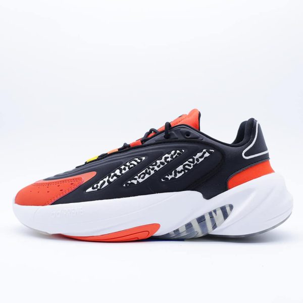 Tenis Adidas Ozelia J infantiles unisex. Silueta audaz de inspiración noventera con estampado animal print, detalles naranja y cómoda amortiguación Adiprene.