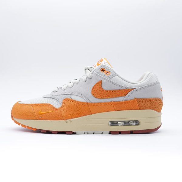 Tenis para hombre Nike Air Max 1 en combinación de naranja "Magma" y gris. Diseño con patrón tipo safari.
